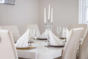 A dining table set for four with white tablecloths, clear glassware, and a candelabra centerpiece. - Large 6 Bed Windsor Stay Near Legoland M4 (Maidenhead)