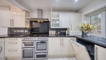 Una cocina moderna con electrodomésticos de acero inoxidable, armarios blancos y un ventanal que proporciona luz natural.