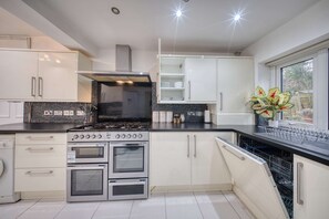 Una cocina moderna con electrodomésticos de acero inoxidable, armarios blancos y un ventanal que proporciona luz natural.
