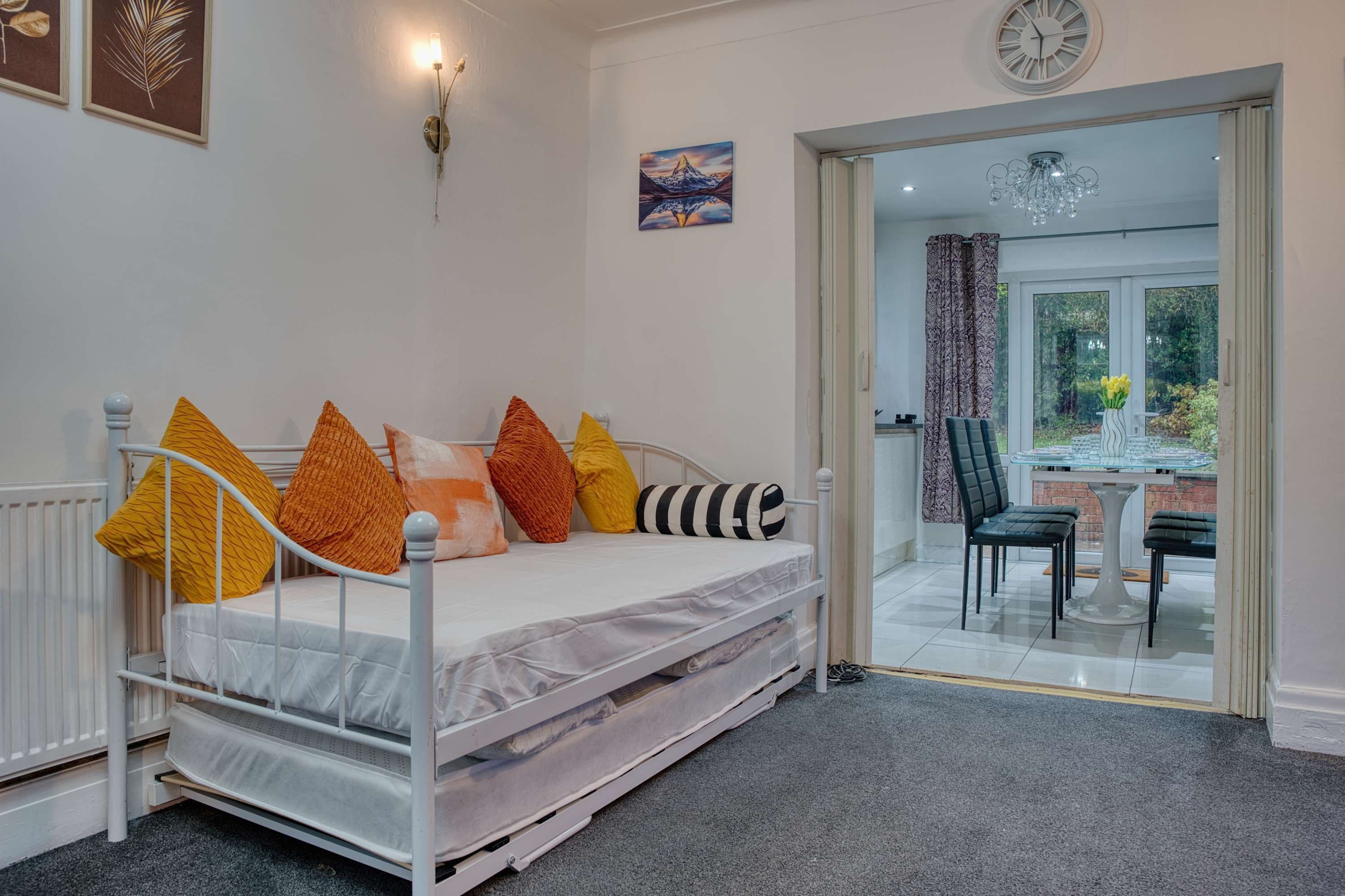 A bedroom with a bed, a window, a door leading to a balcony, and a wall-mounted clock.