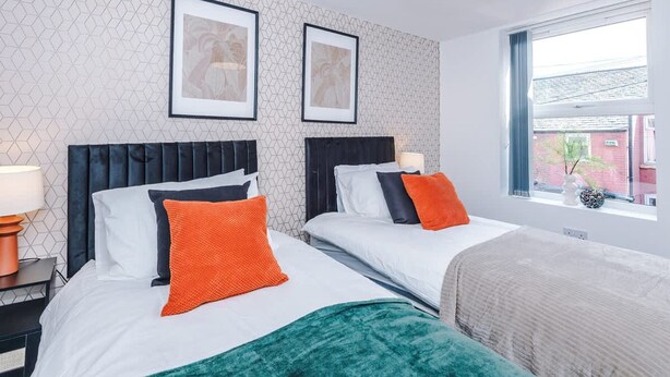Ett hotellrum med två sängar, ett fönster med utsikt över en byggnad och en vägg med ett geometriskt mönster.