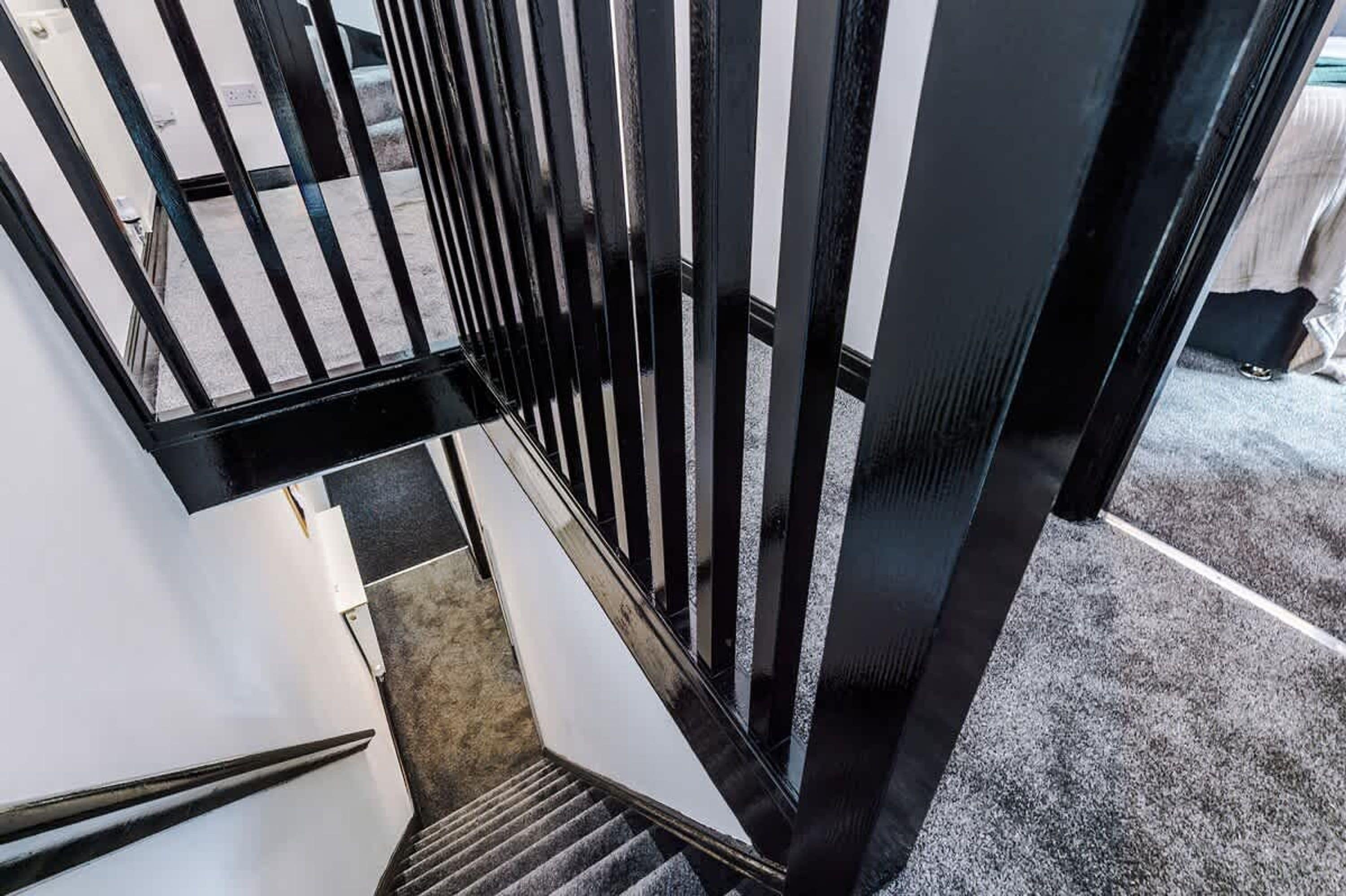 Eine Treppe mit schwarzen Geländern und einem Teppichboden.