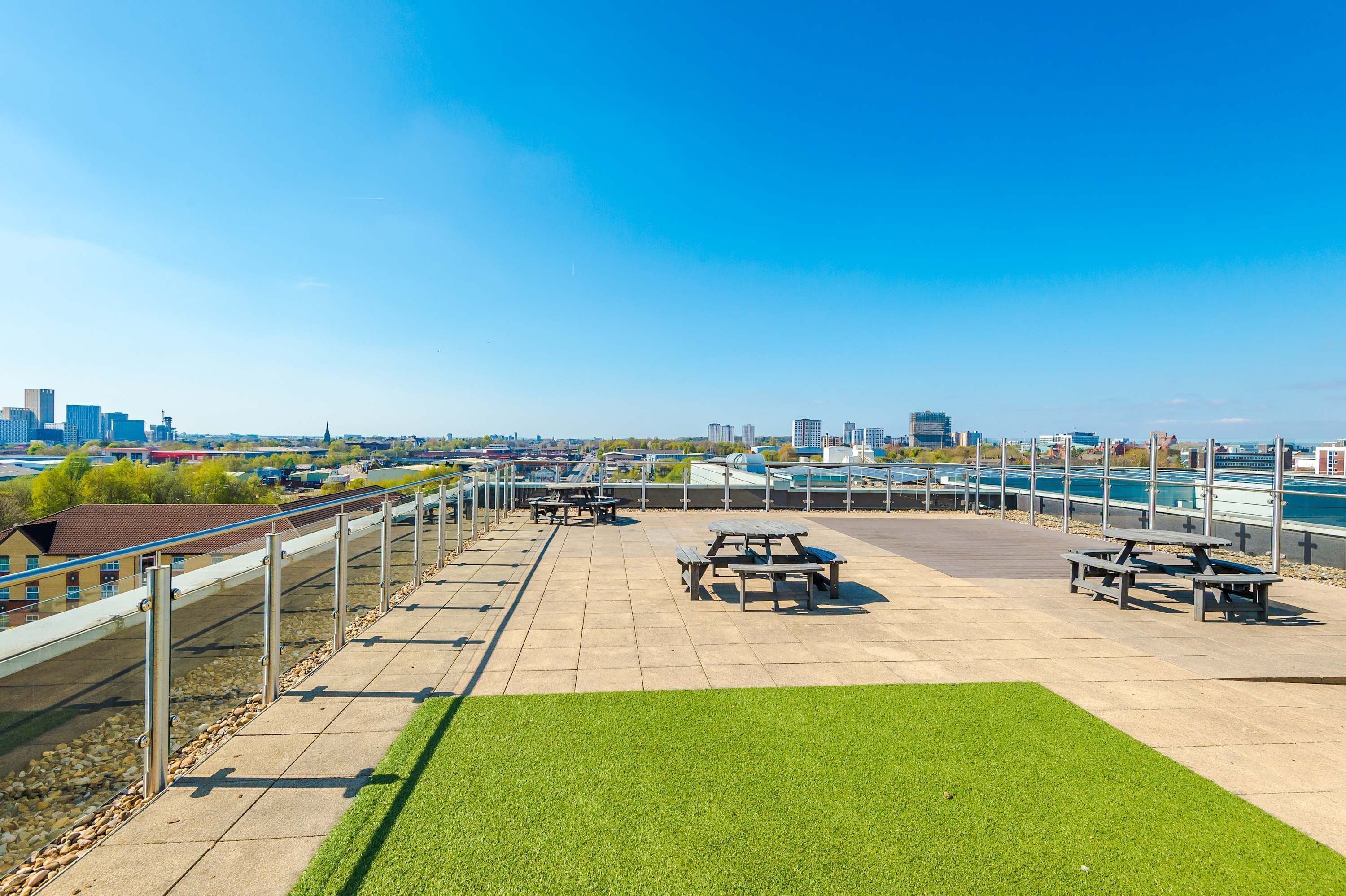 An outdoor patio with picnic tables and a view of a city skyline.