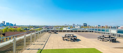 An outdoor patio with picnic tables and a view of a city skyline.