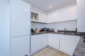 A modern kitchen with white cabinetry, a built-in oven, and a granite countertop. - Modern 2 Bed Duplex Free Parking Wi Fi (Salford)