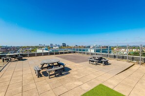 Una terraza en la azotea con mesas de picnic y vistas del horizonte urbano.