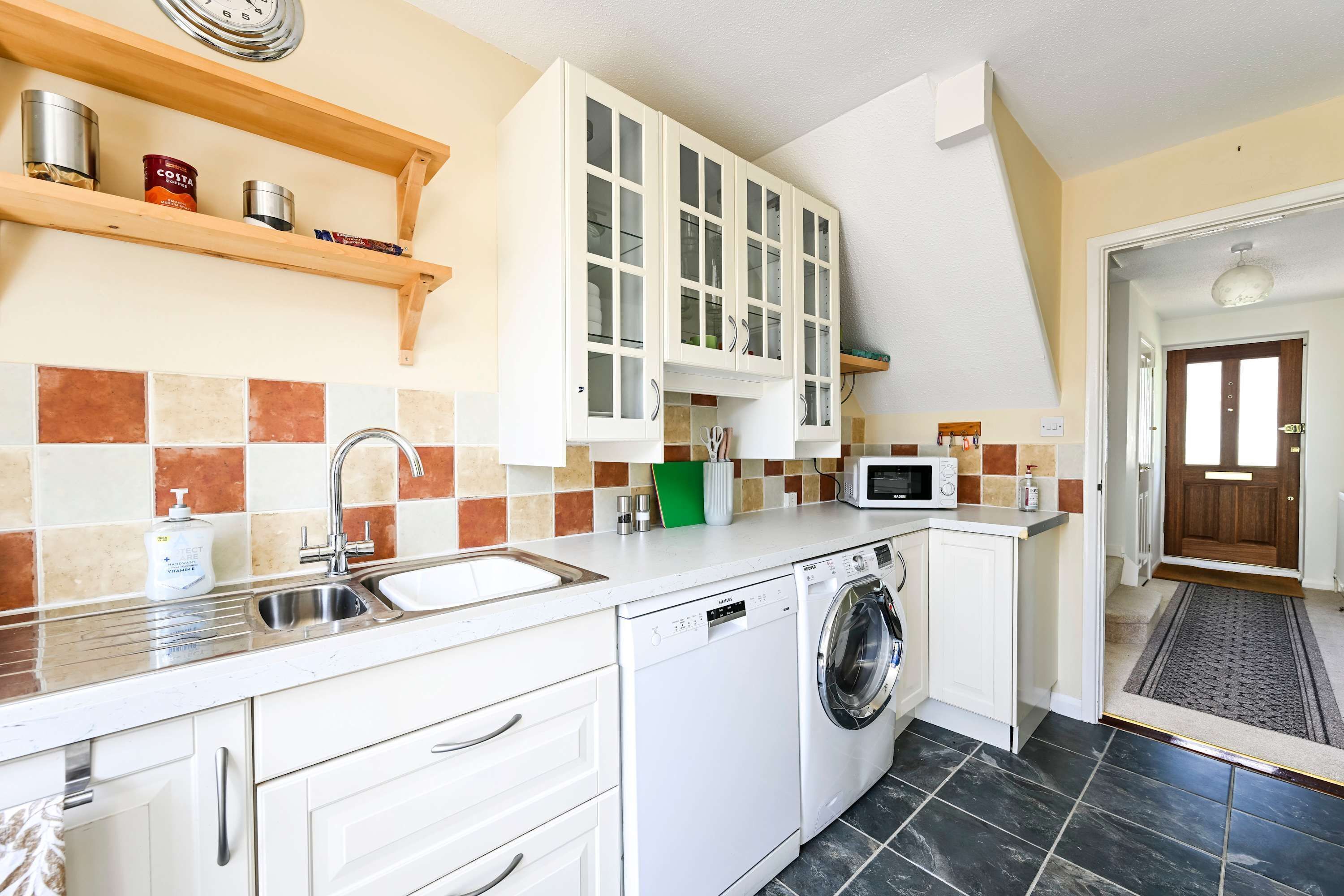 A compact kitchen with a washing machine, a microwave, and a sink.