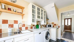 Een kleine keuken met een wasmachine, een magnetron en een spoelbak.