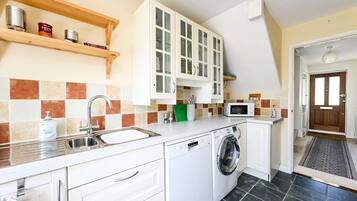 A compact kitchen with a washing machine, a microwave, and a sink.