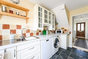A compact kitchen with a washing machine, a microwave, and a sink. - Spacious 3bed Home in Maidenhead Sleeps 6 (Maidenhead)