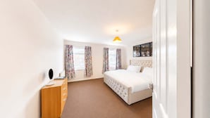 Ein Hotelzimmer mit einem Bett, einer Holzkommode, einem Nachttisch und einem an der Wand hängenden Kunstwerk.