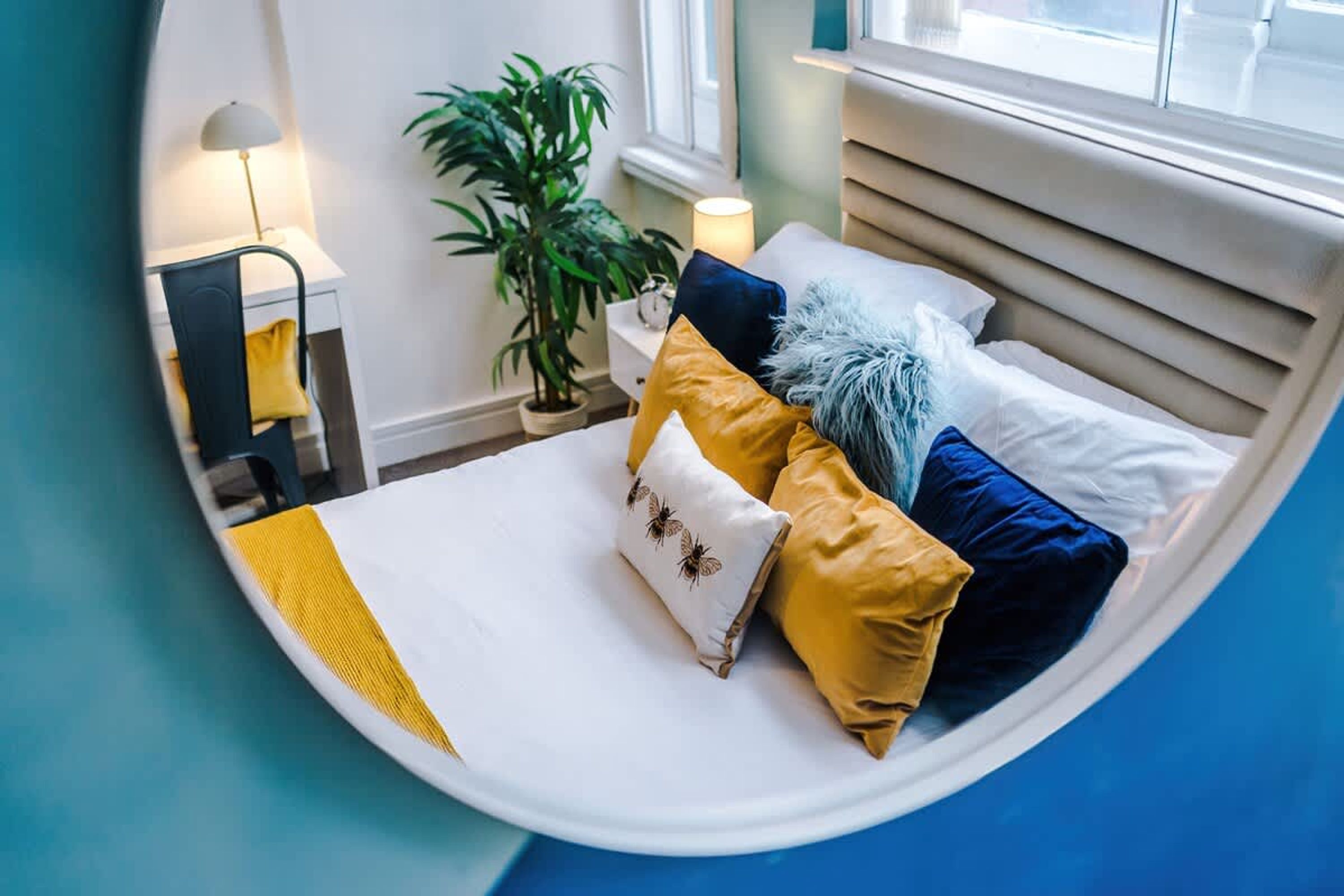 Una cama bien hecha con varias almohadas y una mesita de noche con lámpara.