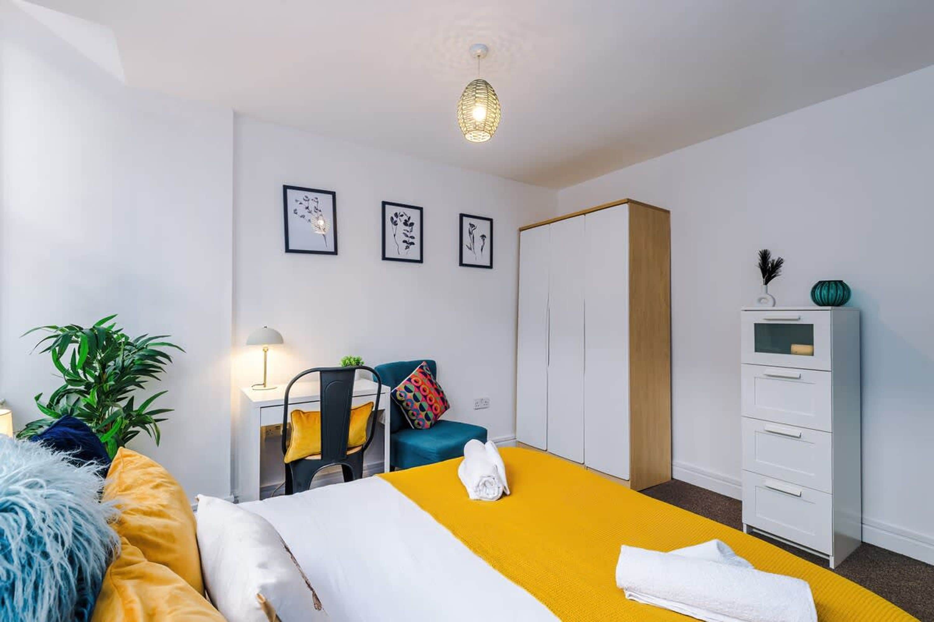Ein Hotelzimmer mit einem Bett, einem Schreibtisch, einem Stuhl, einem Kleiderschrank und einer Pflanze.
