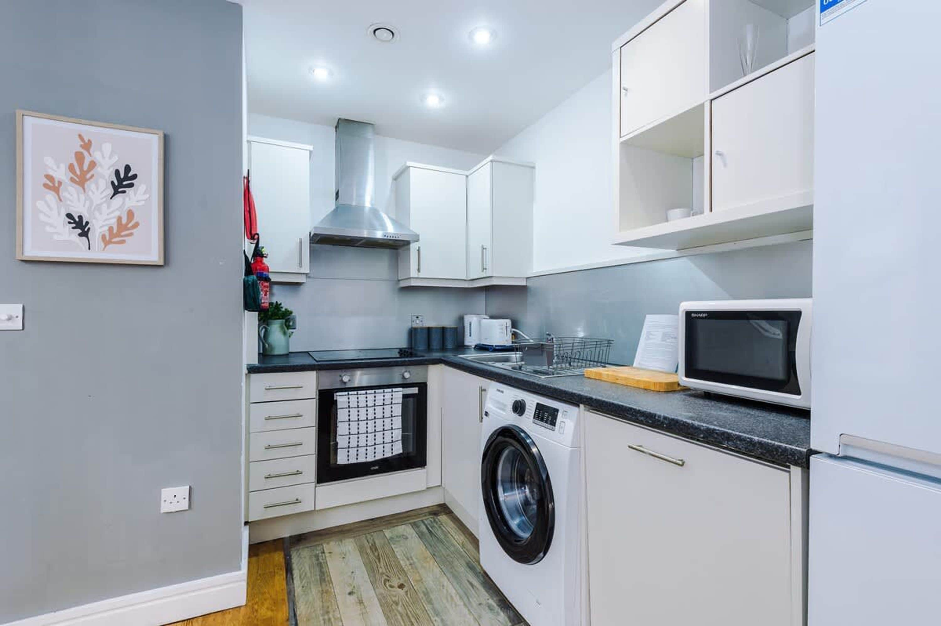 A compact kitchen with a washing machine, a microwave, and a stove.