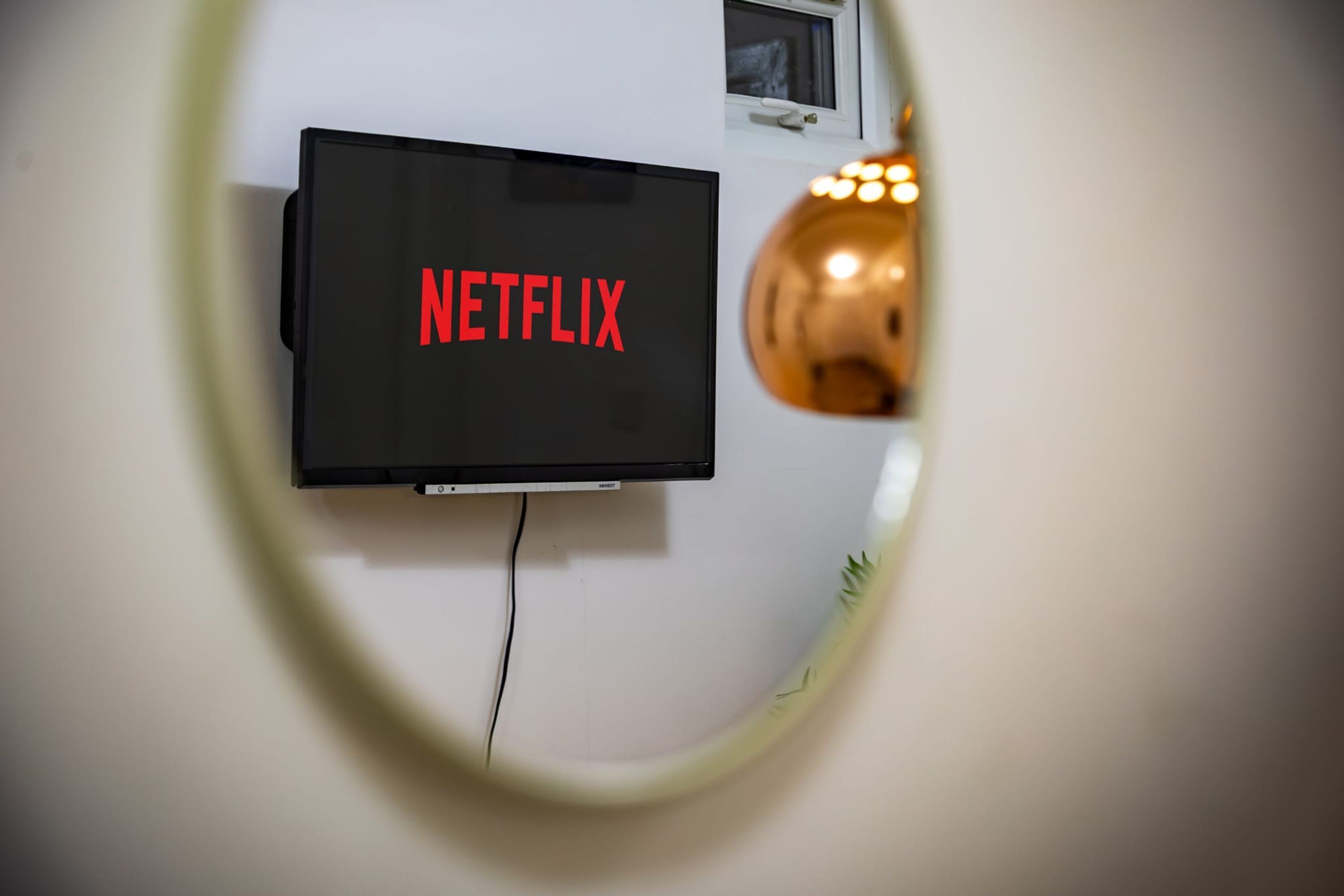Un televisor montado en la pared mostrando la palabra 'NETFLIX' en la pantalla.