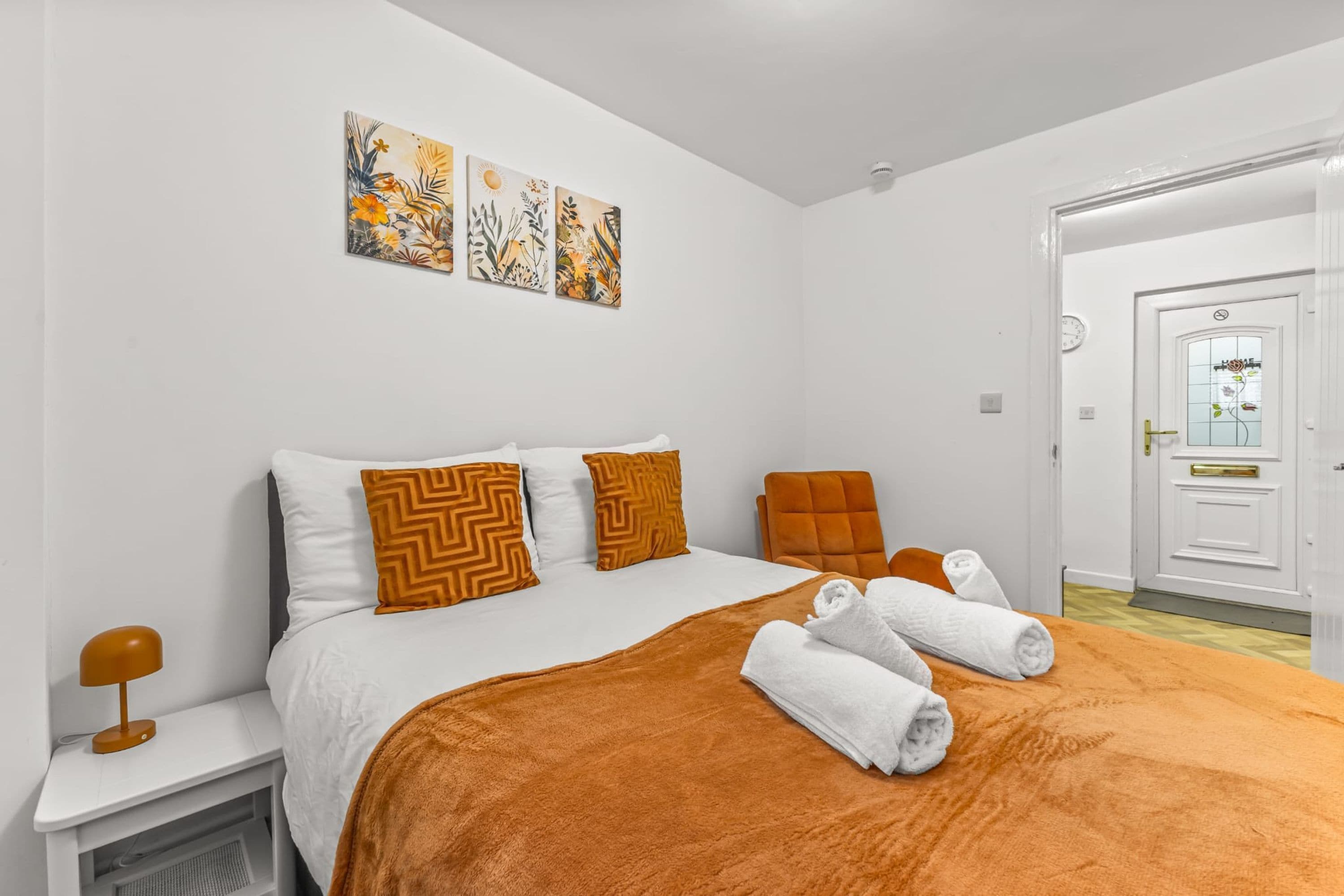 Una habitación de hotel con una cama, una mesita de noche, una silla y una puerta.