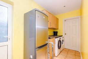 Eine kleine Küche mit Kühlschrank, Waschmaschine und Holzschränken.