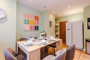A dining area with a table set for four, chairs, a refrigerator, and a wall with motivational posters. - Elite 5BR Manchester Hub Fast Wifi M56 Link (Manchester)