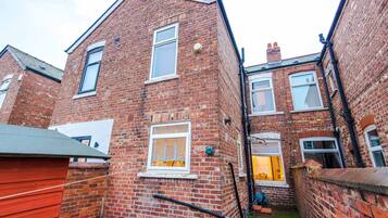 A narrow alleyway between two brick buildings with visible windows and a door.