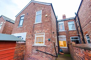 A narrow alleyway between two brick buildings with visible windows and a door. - Bright 3BR Home Manchester Wi-fi Parking (Manchester)