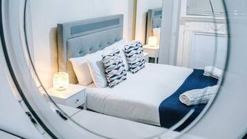 A hotel room with a bed, nightstands, a lamp, and a mirror.