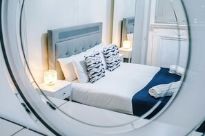 A hotel room with a bed, nightstands, a lamp, and a mirror. - Bright 3BR Home Manchester Wi-fi Parking (Manchester)
