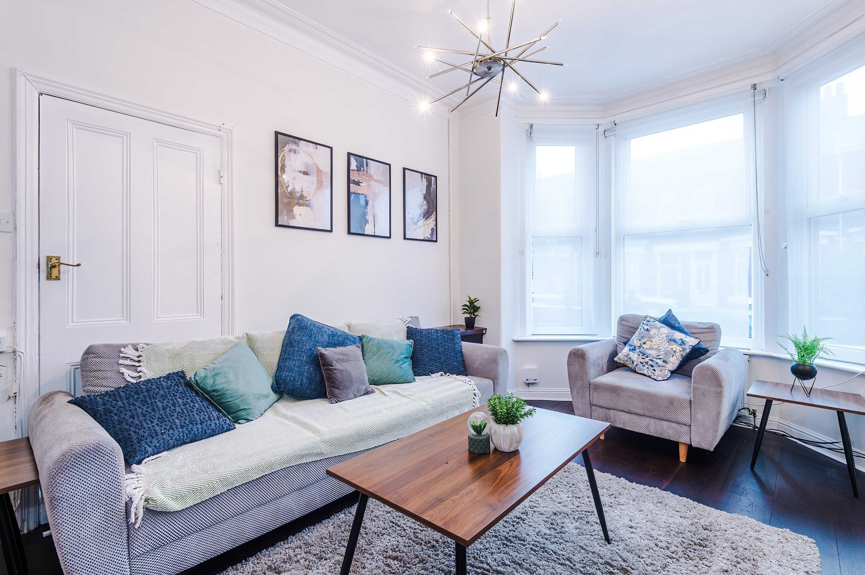 A living room with a sofa, armchairs, a coffee table, and a chandelier.