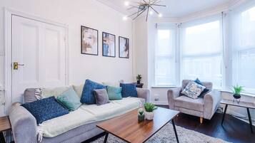A living room with a sofa, armchairs, a coffee table, and a chandelier.