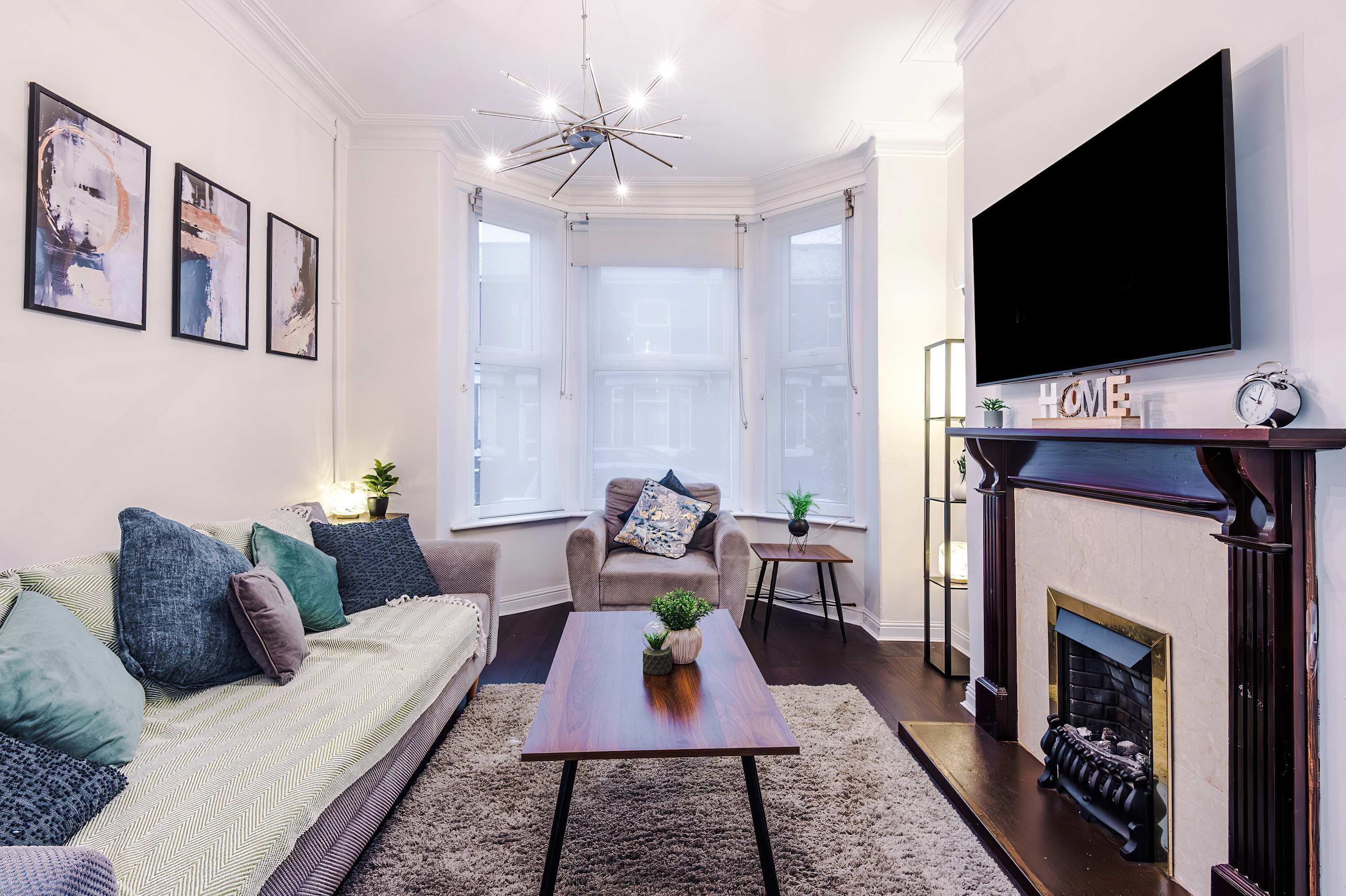 A living room with a sofa, coffee table, fireplace, and a TV mounted on the wall.