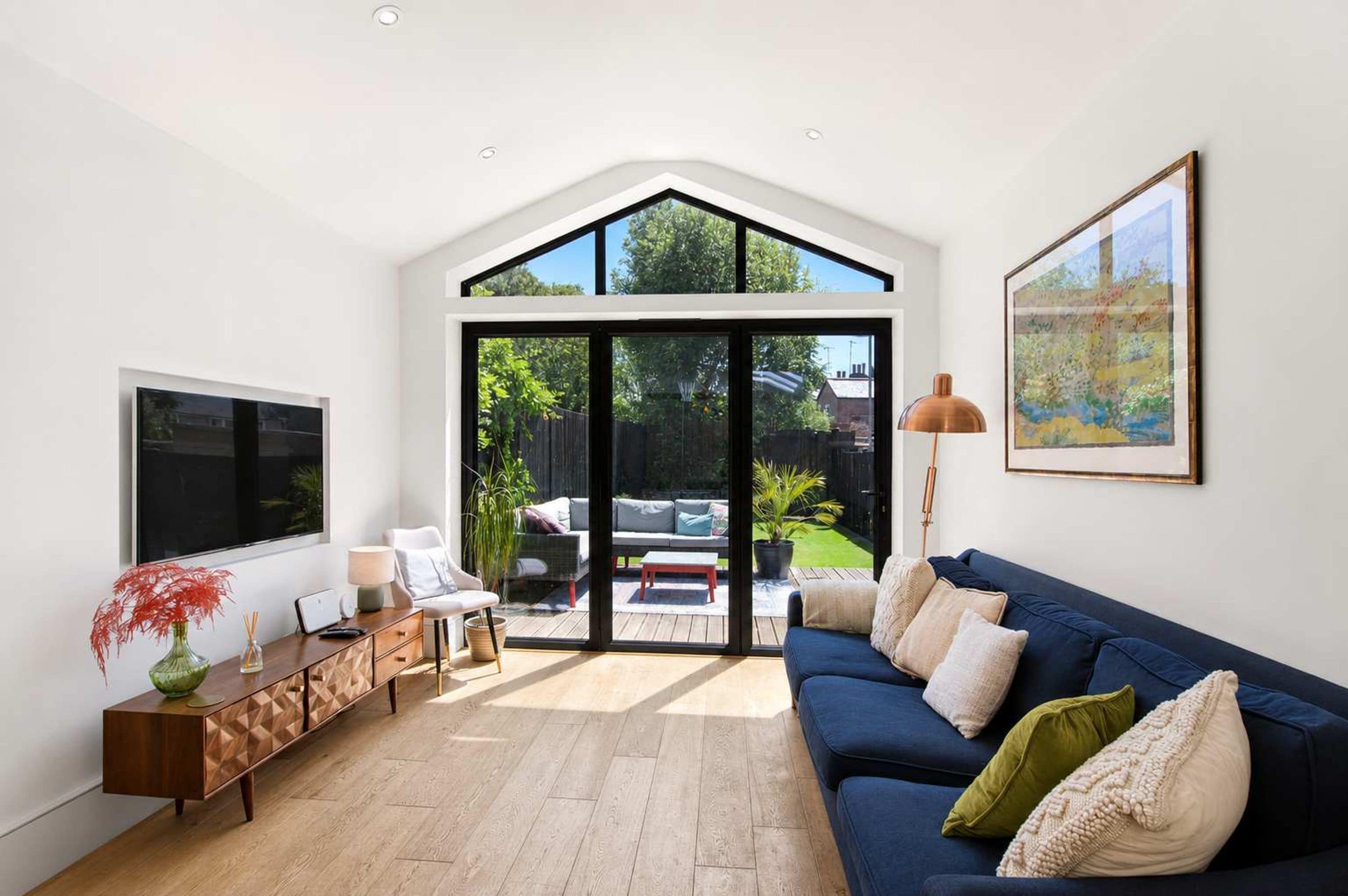 Uma sala de estar moderna com uma TV grande, um sofá, uma mesa de centro e um espaço de jantar com mesa e cadeiras.