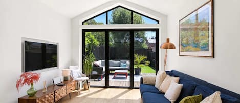A modern living room with a large TV, a sofa, a coffee table, and a dining area with a table and chairs.