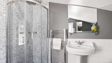 A modern bathroom with a glass-enclosed shower, a white sink, and a mirror above the sink.