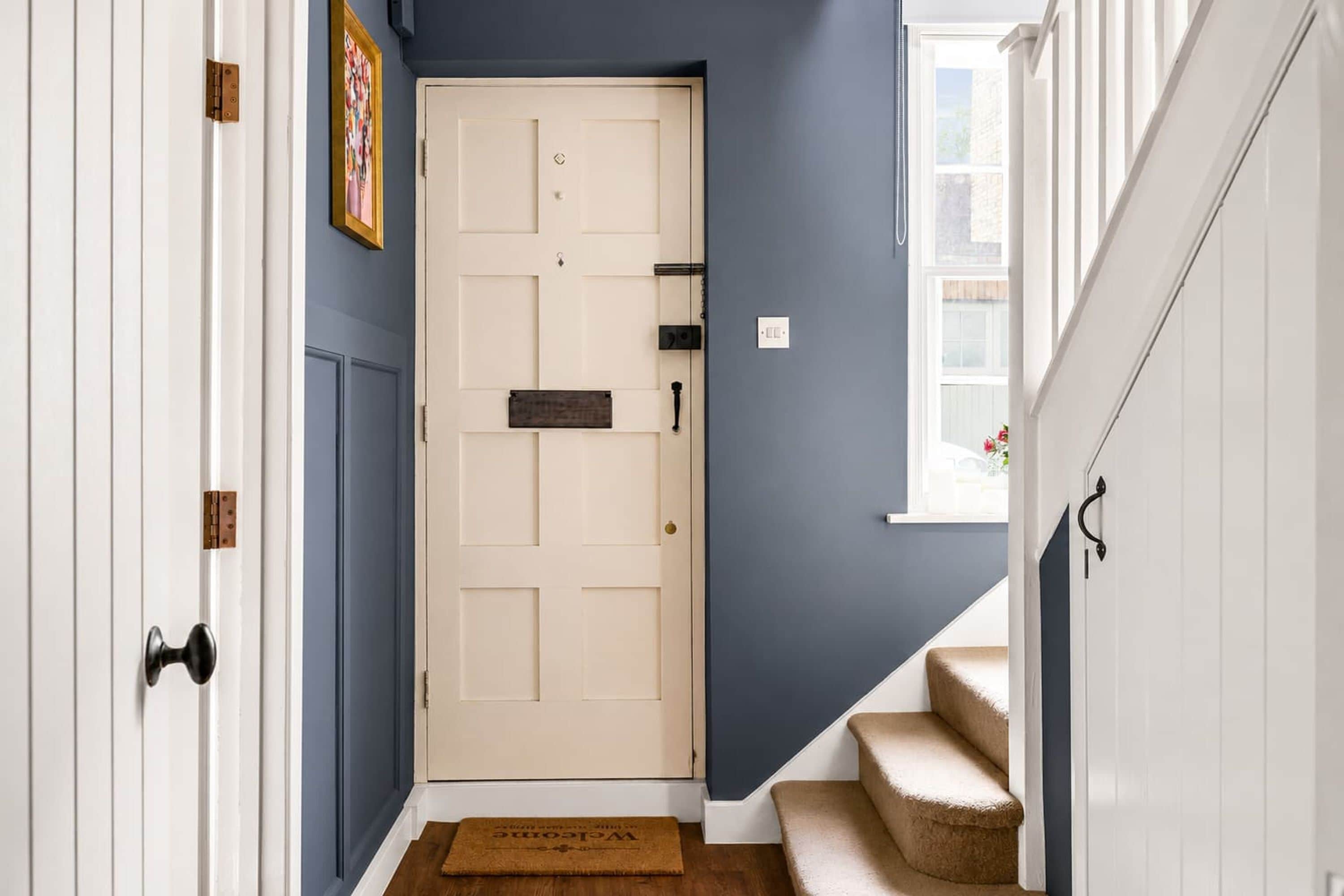A hallway with a door, a window, and a staircase.