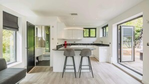 Cozinha moderna com ilha central, dois banquetes e vista para o exterior através de grandes janelas.