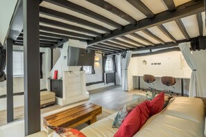 A spacious room with a high ceiling, a fireplace, a television, and a seating area with a sofa and chairs. - Historic Cambridgeshire Cottage Retreat With Hot Tub (Cambridge)