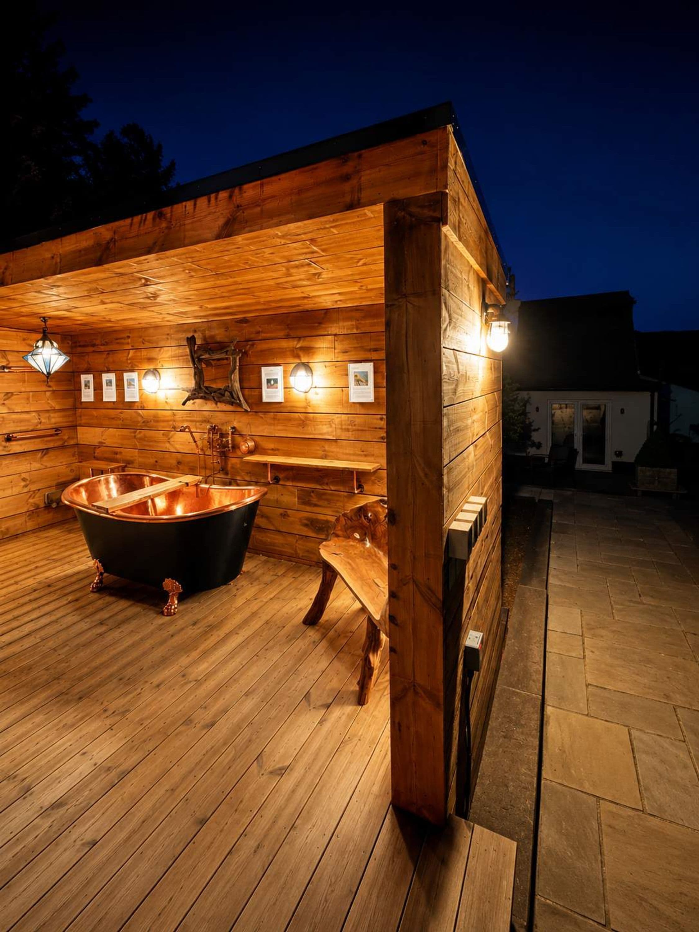 Une cabane en bois dotée d’une grande baignoire, de murs en bois et d’un sol en pierre.