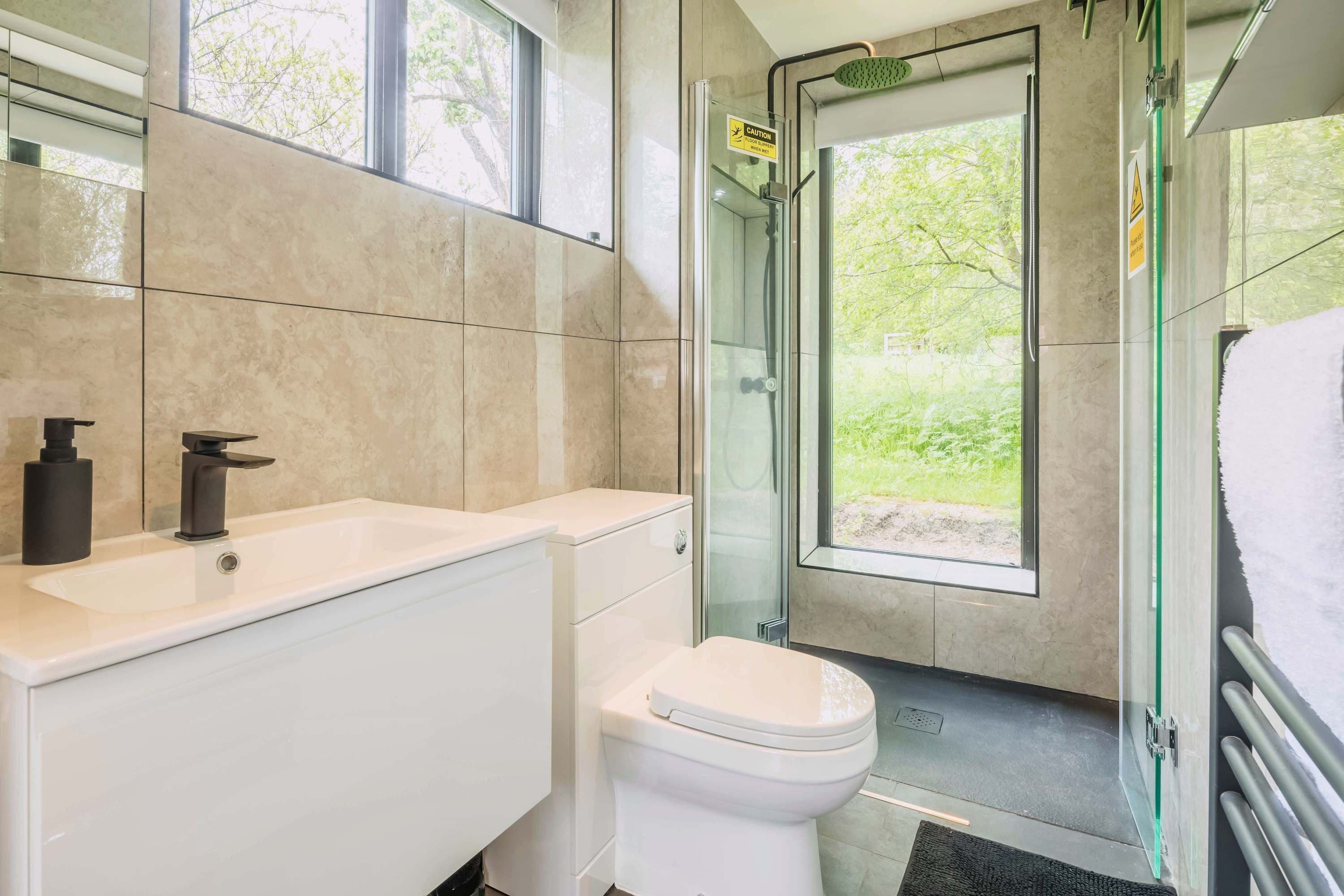 Een moderne badkamer met toilet, wastafel en douche.