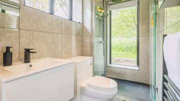 Een moderne badkamer met toilet, wastafel en douche.