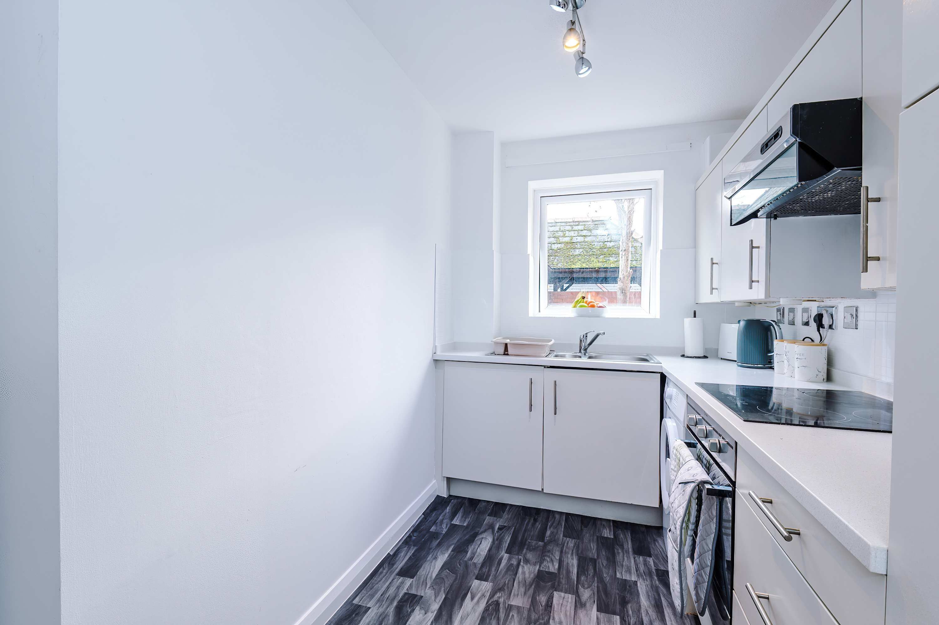 A compact kitchen with white cabinets, a window, and a black countertop.