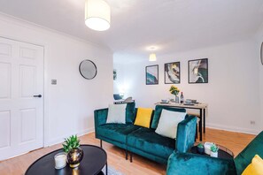 Una sala de estar moderna con un sofá color turquesa, un espejo redondo y arte abstracto en la pared.