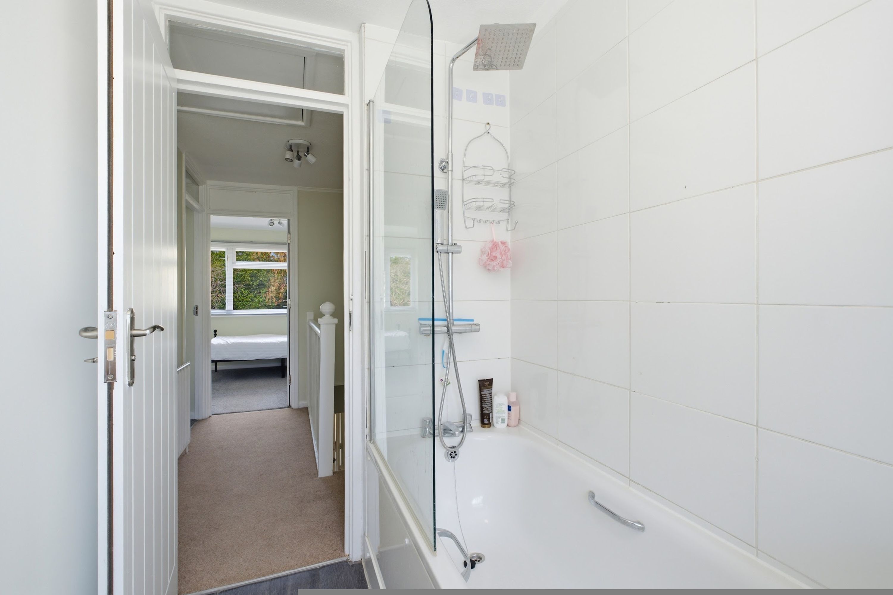 A bathroom with a shower, a glass door, and a towel rack.