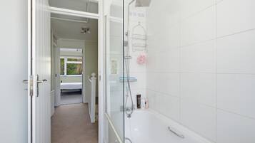 A bathroom with a shower, a glass door, and a towel rack.