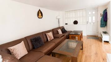 A modern living room with a brown leather sofa, a glass coffee table, and a white cabinet.