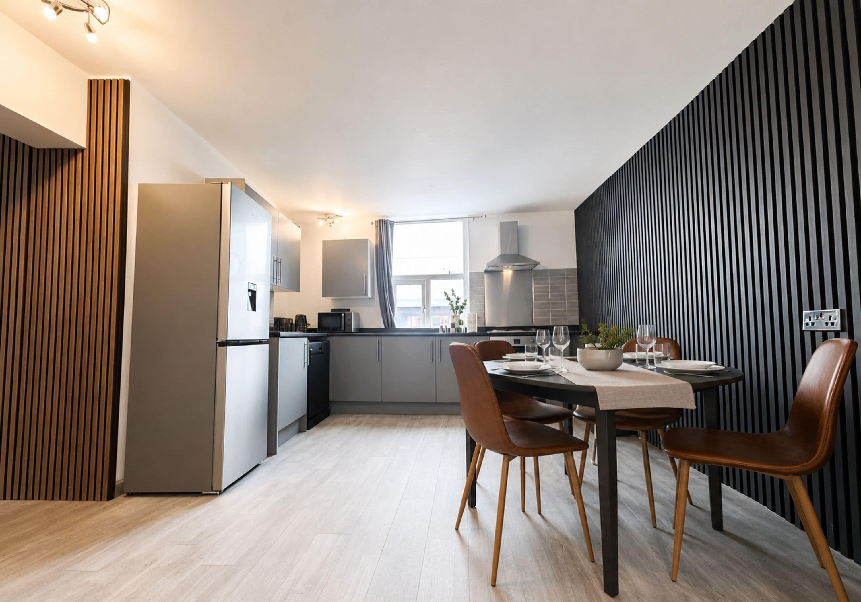 Une cuisine moderne avec un coin repas, comprenant un réfrigérateur, un four à micro-ondes et des placards.