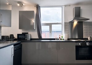 A modern kitchen with a built-in oven, a microwave, and a stainless steel range hood. - 2 Bed Manchester Free Parking Sleeps 4 (Manchester)