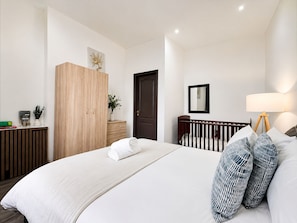 A bedroom with a bed, a wooden wardrobe, a dark door, a bedside table with a lamp, and a small potted plant. - 2 Bed Manchester Free Parking Sleeps 4 (Manchester)