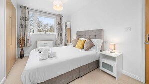 A modern bedroom with a large bed, bedside tables, a window with curtains, and a ceiling light. - Sleek 2BR Edinburgh Near Murrayfield Sleeps 4 (Edinburgh)