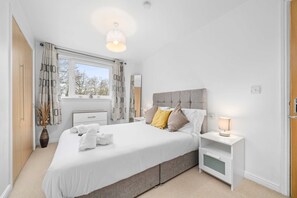 A modern bedroom with a large bed, bedside tables, a window with curtains, and a ceiling light. - Sleek 2BR Edinburgh Near Murrayfield Sleeps 4 (Edinburgh)