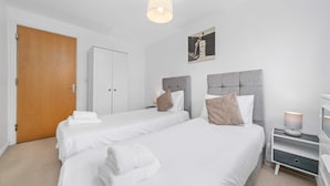 A hotel room with two beds, a wardrobe, a bedside table with a lamp, and a picture on the wall. - Sleek 2BR Edinburgh Near Murrayfield Sleeps 4 (Edinburgh)