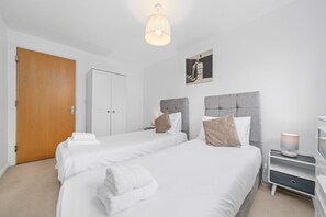 A hotel room with two beds, a wardrobe, a bedside table with a lamp, and a picture on the wall. - Sleek 2BR Edinburgh Near Murrayfield Sleeps 4 (Edinburgh)